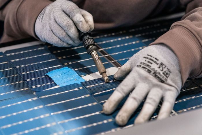 A close-up image of a technician's hands working on a solar panel.