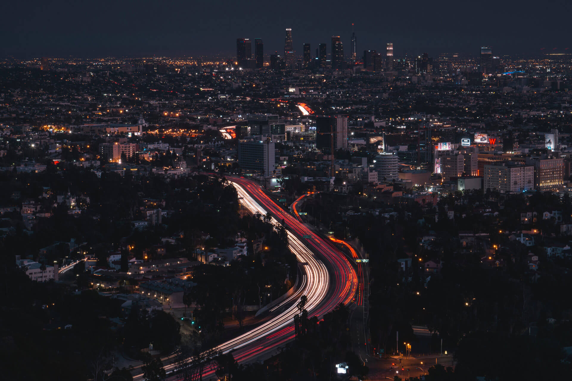 The Los Angeles cityscape at night, illuminated by lights from buildings and cars on the highway.